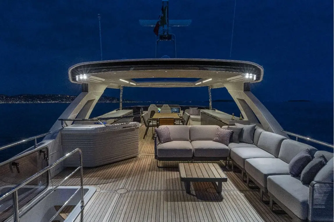 Luxurious yacht interior at night featuring a spacious lounge area with grey sofas and a wooden coffee table.